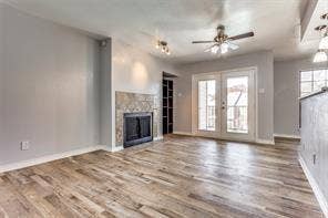 5726 Marvin Loving Drive, #221, Garland, TX 75043 Wood-finish flooring, fireplace with stone tile surround, double French doors, ceiling fan, and recessed lighting