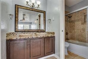 5726 Marvin Loving Drive, #221, Garland, TX 75043 Dual vessel sinks, dark wood-finish vanity, decorative framed mirror, integrated tub with shower, and tile surround