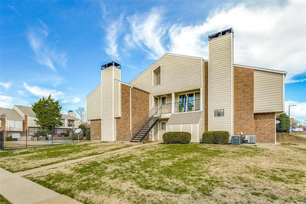 5726 Marvin Loving Drive, #221, Garland, TX 75043 Two-story building featuring brick and siding exterior, exterior metal staircase, and an upper-level balcony with metal railing