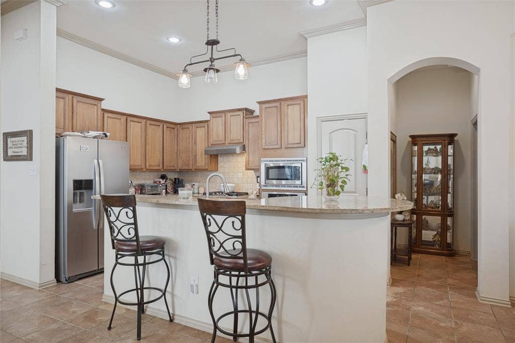 The raised breakfast bar offers casual eat-in seating, creating the perfect spot for quick breakfasts, morning coffee, or gathering with family and friends while meals are being prepared.