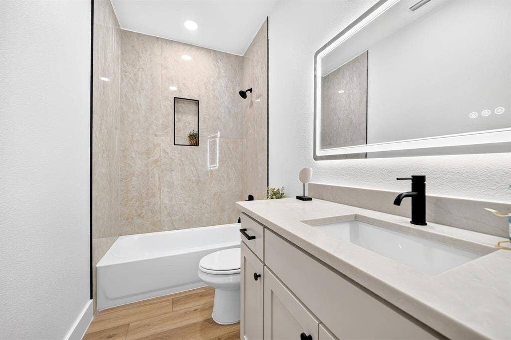 5731 Lewis Court, Athens, TX 75752 Bathtub and shower combination with floor-to-ceiling tiled surround, integrated shower niche, and matte black fixtures