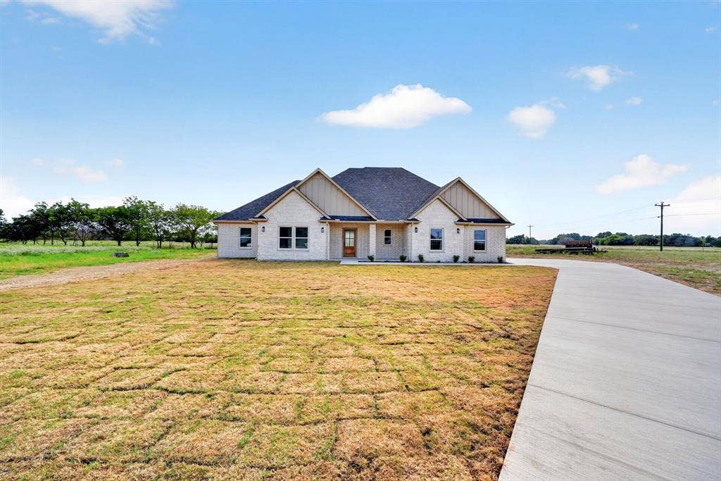 5731 Lewis Court, Athens, TX 75752 Light-colored brick exterior with dark shingle roof, featuring gabled dormers with vertical wood siding