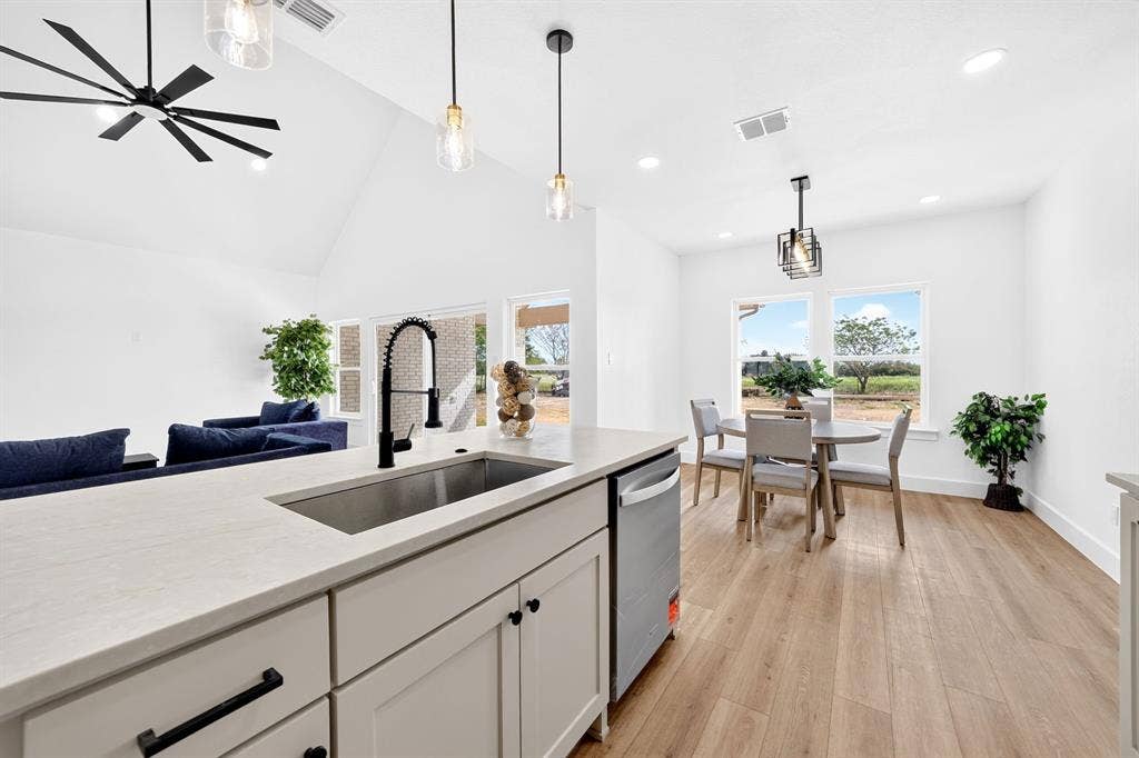 5731 Lewis Court, Athens, TX 75752 Kitchen island with a stainless steel sink and matte black faucet, open-concept layout, vaulted ceiling, recessed lighting, and wood-finish flooring