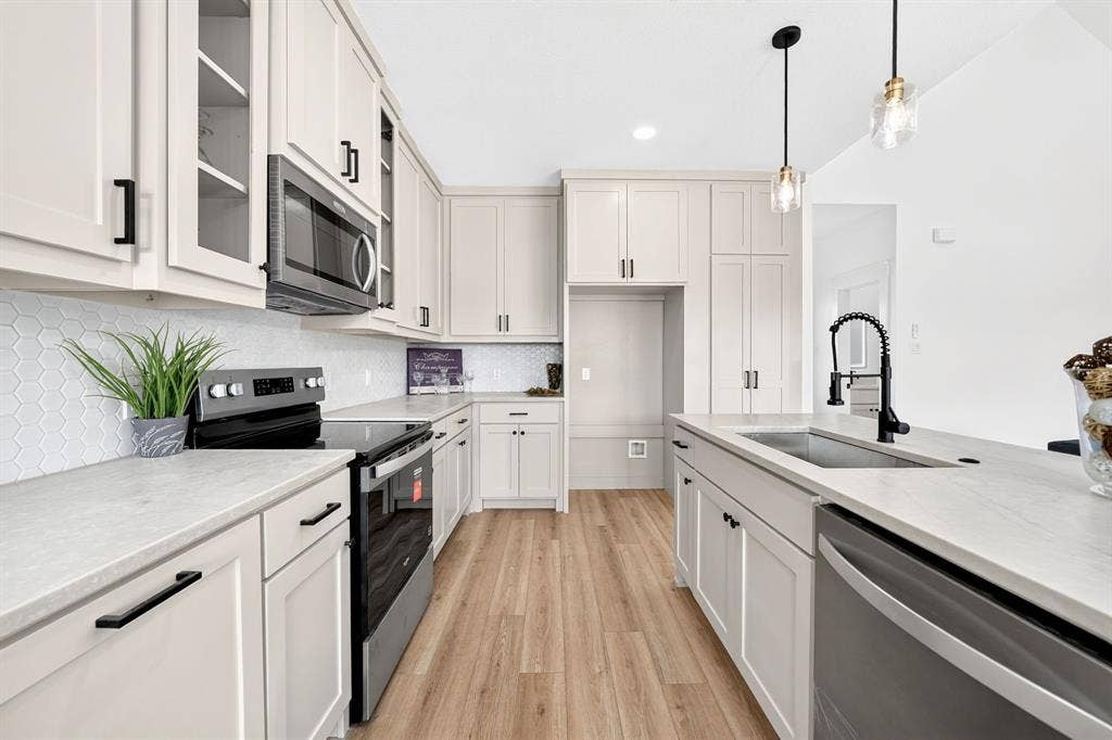 5731 Lewis Court, Athens, TX 75752 Kitchen featuring light cabinetry, a hexagonal tile backsplash, a stainless steel dishwasher, a black electric range, and wood-finish flooring