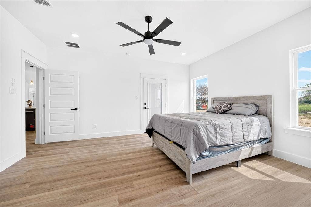 5731 Lewis Court, Athens, TX 75752 Recessed ceiling lighting, wood-finish flooring, two windows with white trim, a ceiling fan with a matte black finish, and a white paneled door with a matte black handle
