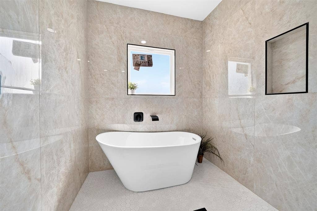 5731 Lewis Court, Athens, TX 75752 Freestanding soaking tub with wall-mounted matte black fixtures, set against full-height polished tile walls