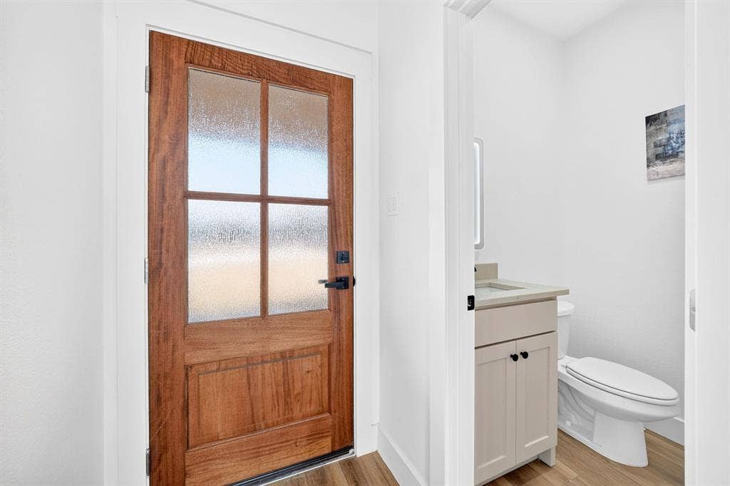 5731 Lewis Court, Athens, TX 75752 Wood-paneled door with frosted glass inserts, matte black hardware, wood-finish flooring, and a vanity with a light-colored countertop