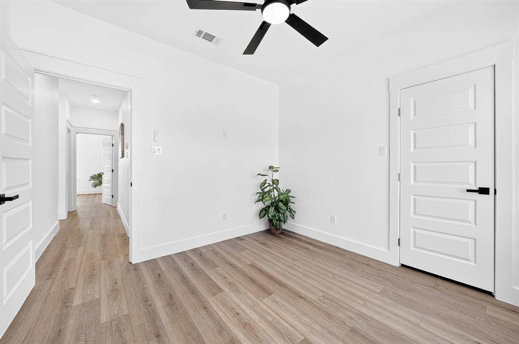5731 Lewis Court, Athens, TX 75752 Wood-finish flooring, white walls, five-panel interior doors with black hardware, and a ceiling fan with integrated lighting