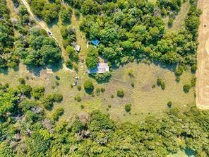 6630 Prather Road, Springtown, TX 76082 Wooded acreage featuring a single-story residence with a light-toned roof, an additional outbuilding, and expansive cleared areas