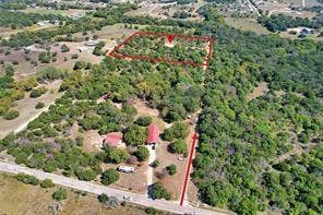 6630 Prather Road, Springtown, TX 76082 Expansive wooded lot with a detached structure featuring a red roof, bordered by a paved road