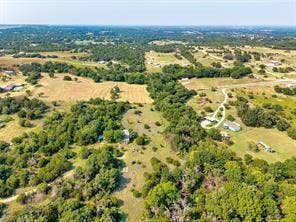 6630 Prather Road, Springtown, TX 76082 Expansive land offering diverse natural features, including open fields, dense tree coverage, and a winding unpaved road