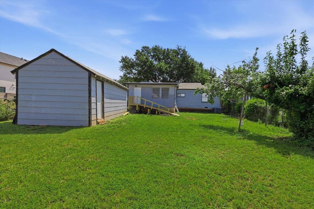 6807 Prosper Street, Dallas, TX 75209 Wide backyard perspective highlighting the open grassy lawn, detached garage, rear exterior, and fenced perimeter. The yard offers an impressive amount of usable outdoor space with room for seating, recreation, gardening, or additional landscaping. This view helps capture the scale of the lot and the lifestyle potential available beyond the home itself.