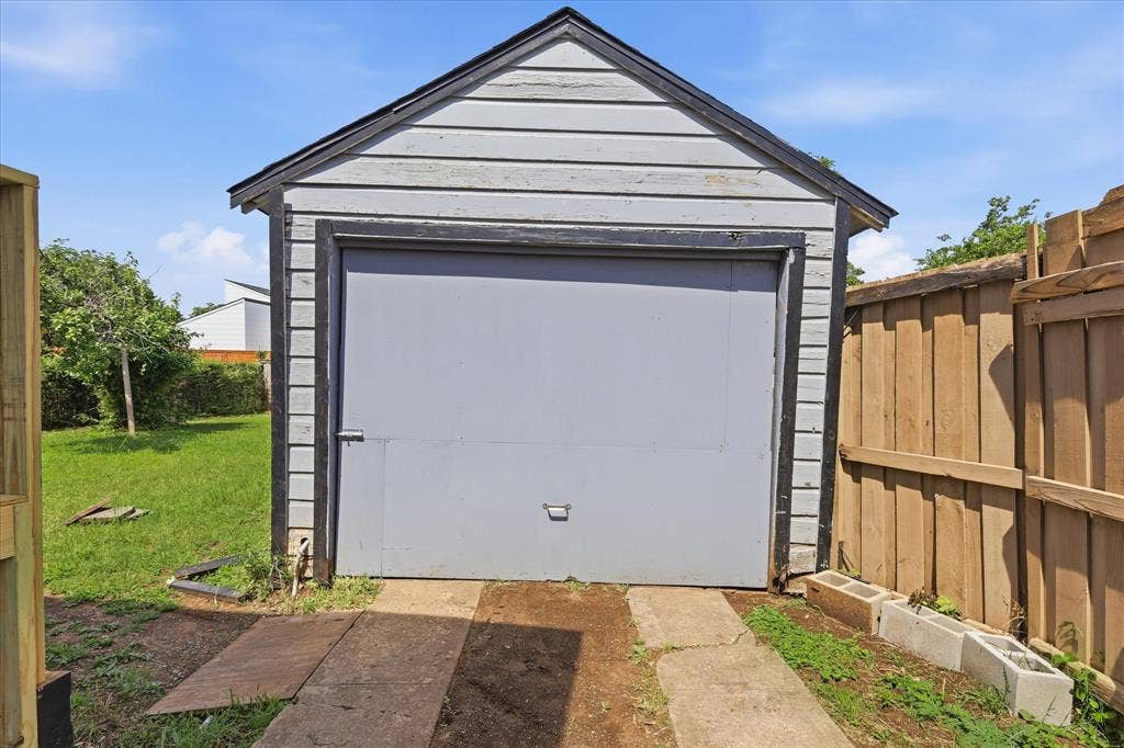 6807 Prosper Street, Dallas, TX 75209 Detached garage view with driveway-style approach, fenced side area, and access into the backyard. This structure provides valuable utility for parking, storage, tools, hobbies, or workshop potential. The garage adds a major functional advantage to the property, especially for buyers who need extra space beyond the home’s interior square footage.
