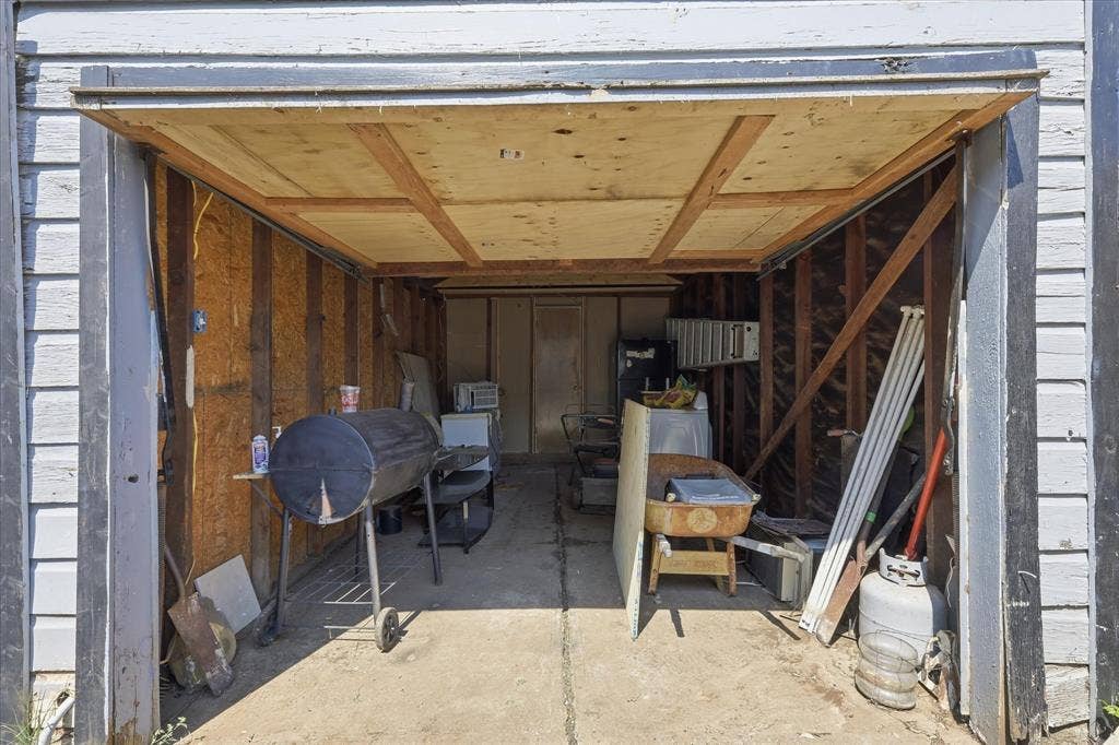 6807 Prosper Street, Dallas, TX 75209 Interior garage view showing a concrete floor, exposed framing, overhead door, and flexible storage space. This area offers practical utility for tools, lawn equipment, bikes, seasonal items, hobbies, or workshop use, adding functional value beyond the home’s interior living space.