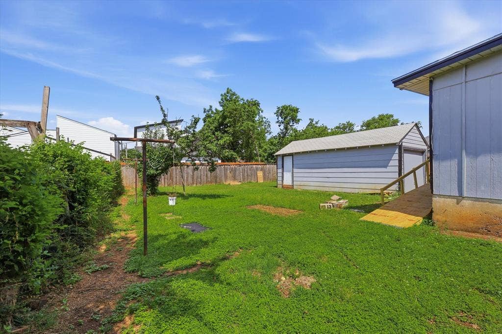 6807 Prosper Street, Dallas, TX 75209 Detached garage exterior with side-entry door and generous lawn space surrounding it. This structure adds valuable flexibility for parking, storage, tools, lawn equipment, hobbies, or workshop use, while its placement within the backyard keeps the main outdoor area open and functional.