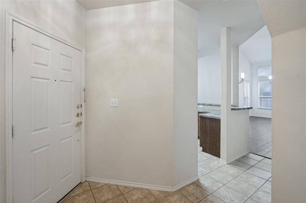 3236 Twist Trail, Plano, TX 75093 Panel-style entry door, tile flooring, granite-look countertop, wood-finish cabinetry, and vaulted ceiling