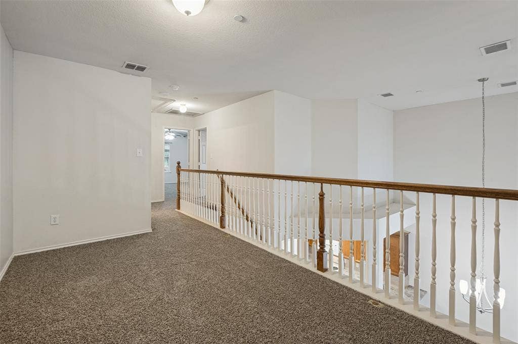 3236 Twist Trail, Plano, TX 75093 Carpeted loft area featuring a wood-finish handrail and painted balusters