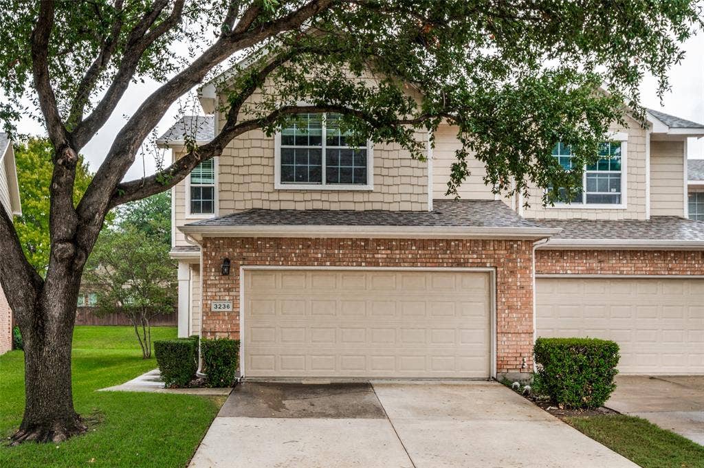 3236 Twist Trail, Plano, TX 75093 Two-story residence featuring a brick and shingle facade, multiple windows, an attached garage, and a concrete driveway