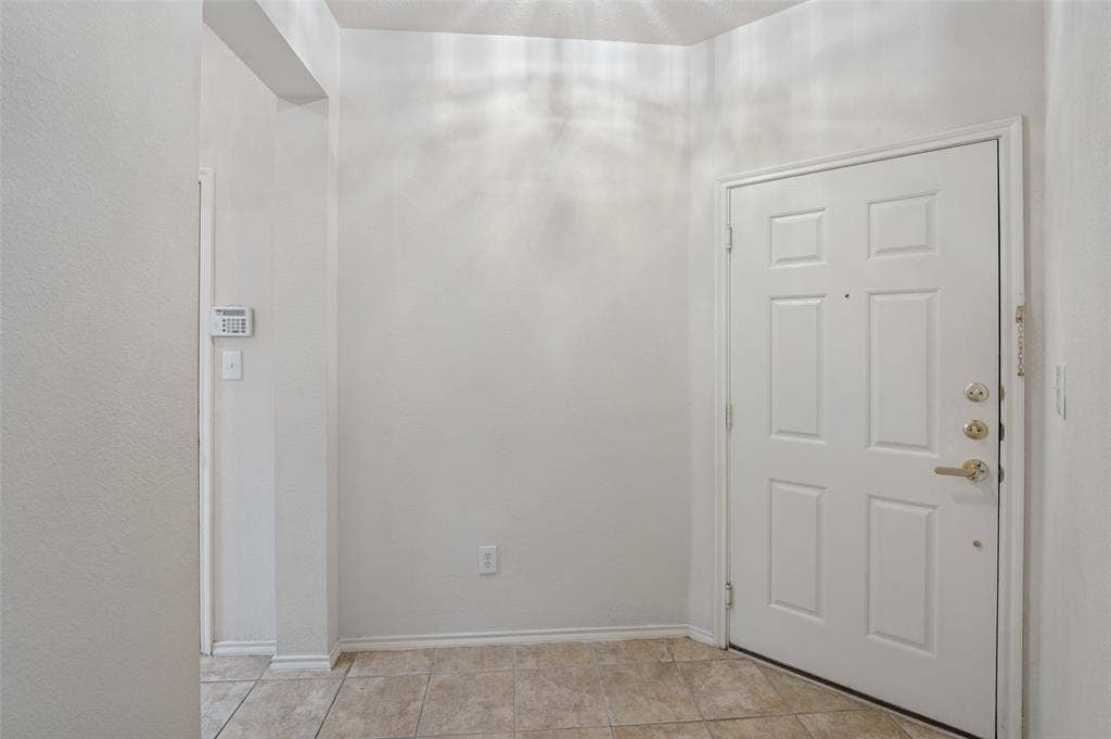 3236 Twist Trail, Plano, TX 75093 White paneled door with brass hardware, light-toned tile flooring, and neutral wall tones
