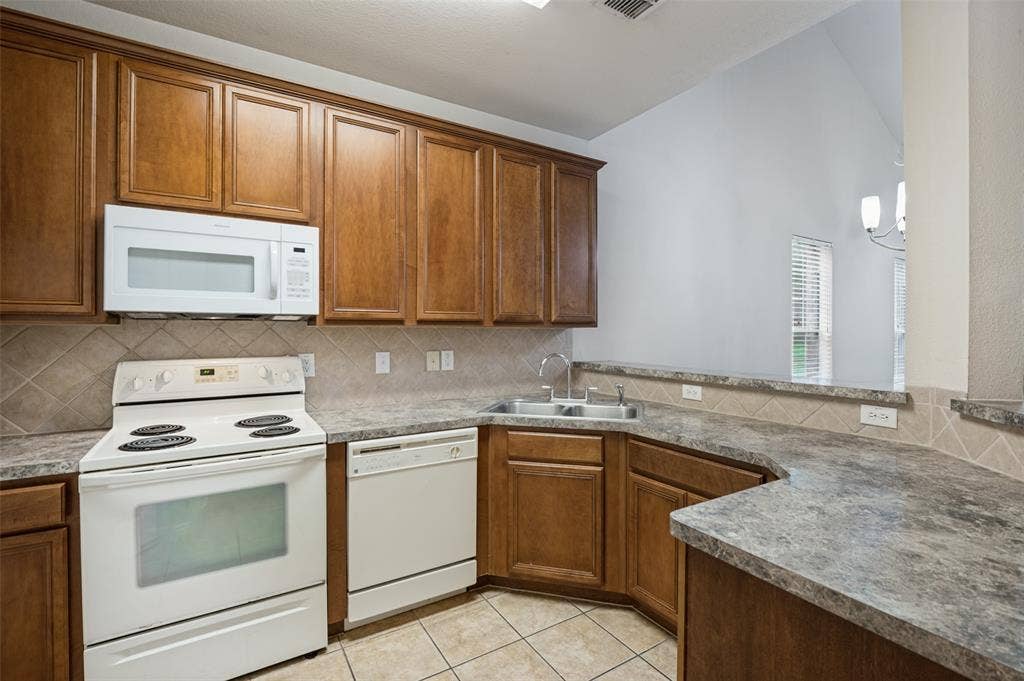 3236 Twist Trail, Plano, TX 75093 Kitchen featuring wood cabinetry, solid surface countertops, white appliances, and a tiled backsplash