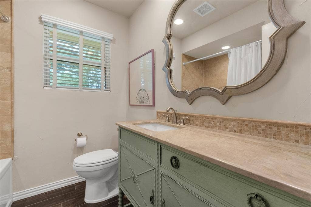 1815 Oates Drive, Dallas, TX 75228 Bathroom featuring a vanity with an integrated sink, a large decorative mirror, and a window with horizontal blinds