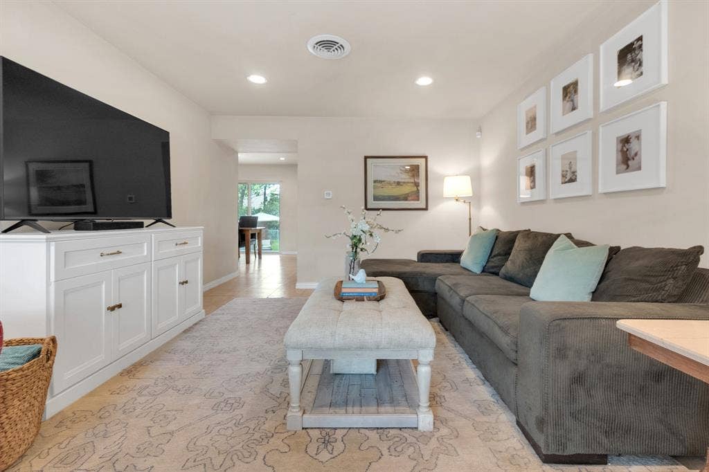 1815 Oates Drive, Dallas, TX 75228 Recessed ceiling lighting illuminates a bright living space featuring light wall tones and a patterned area rug over wood-finish flooring