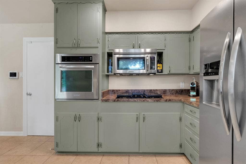 1815 Oates Drive, Dallas, TX 75228 Kitchen featuring wood-finish cabinetry, built-in stainless steel oven, integrated microwave, cooktop, and stone-finish countertops
