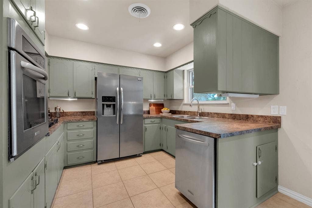1815 Oates Drive, Dallas, TX 75228 U-shaped kitchen featuring sage green cabinetry, a stainless steel side-by-side refrigerator, and stone-finish countertops
