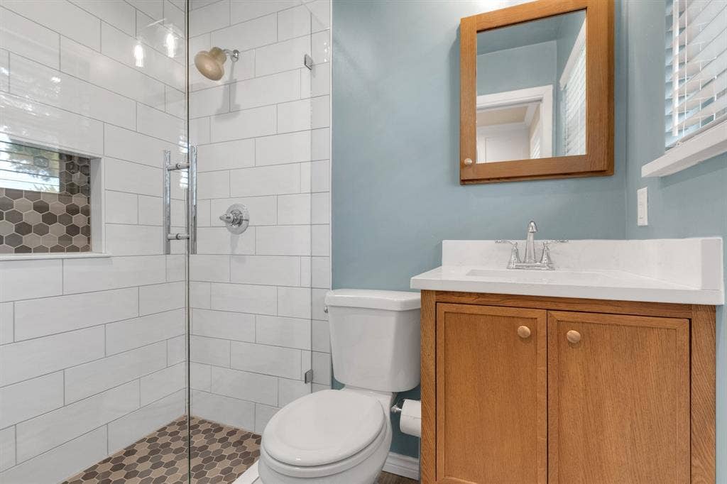 1815 Oates Drive, Dallas, TX 75228 Bathroom featuring a glass-enclosed shower with white subway tile, hexagonal mosaic floor tiling, and a built-in shower niche