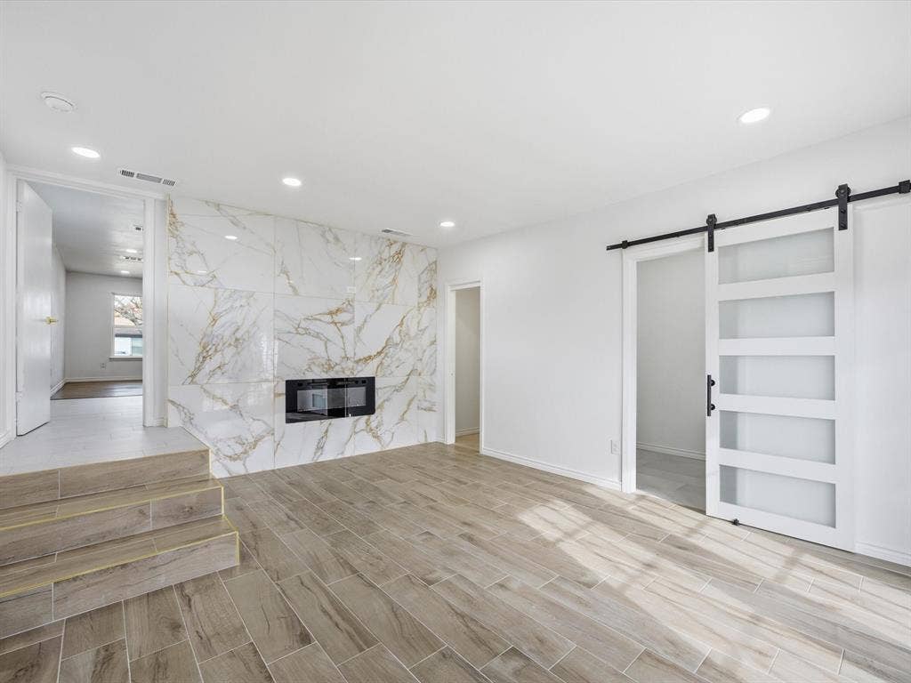 10270 Kilkenny Place, Dallas, TX 75228 Wood-finish flooring, recessed lighting, white walls, and a white barn door with frosted glass panels