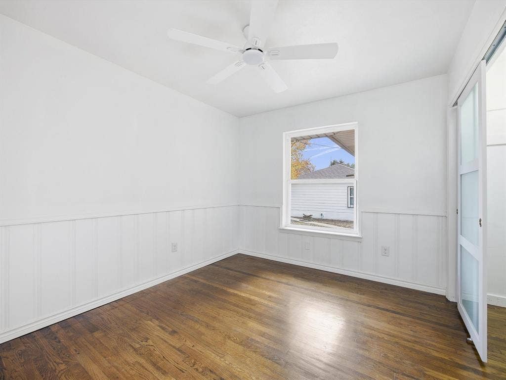 10270 Kilkenny Place, Dallas, TX 75228 Hardwood flooring, white wainscoting, white walls, ceiling fan, and a sliding barn door with frosted panels