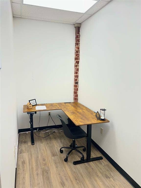 123 W Princeton Drive, #200, Princeton, TX 75407 Wood-finish flooring with black trim, white walls, and exposed brick column