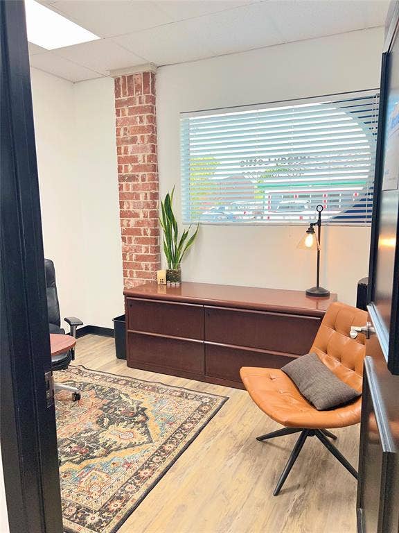 123 W Princeton Drive, #200, Princeton, TX 75407 Wood-finish flooring with a brick accent wall