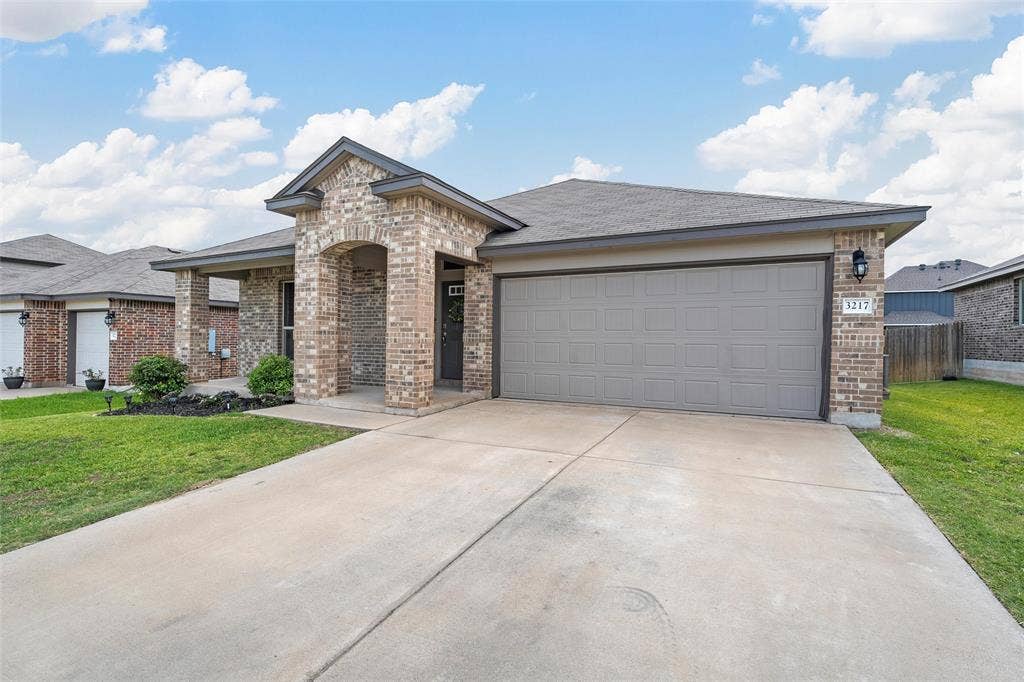 3217 Beutel Road, Lorena, TX 76655 View of front of property with brick siding, driveway, an attached garage, and roof with shingles