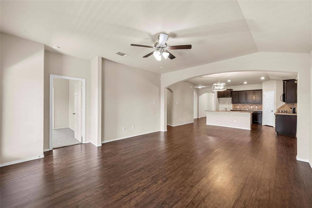 3217 Beutel Road, Lorena, TX 76655 Unfurnished living room with arched walkways, ceiling fan, and dark wood-style floors