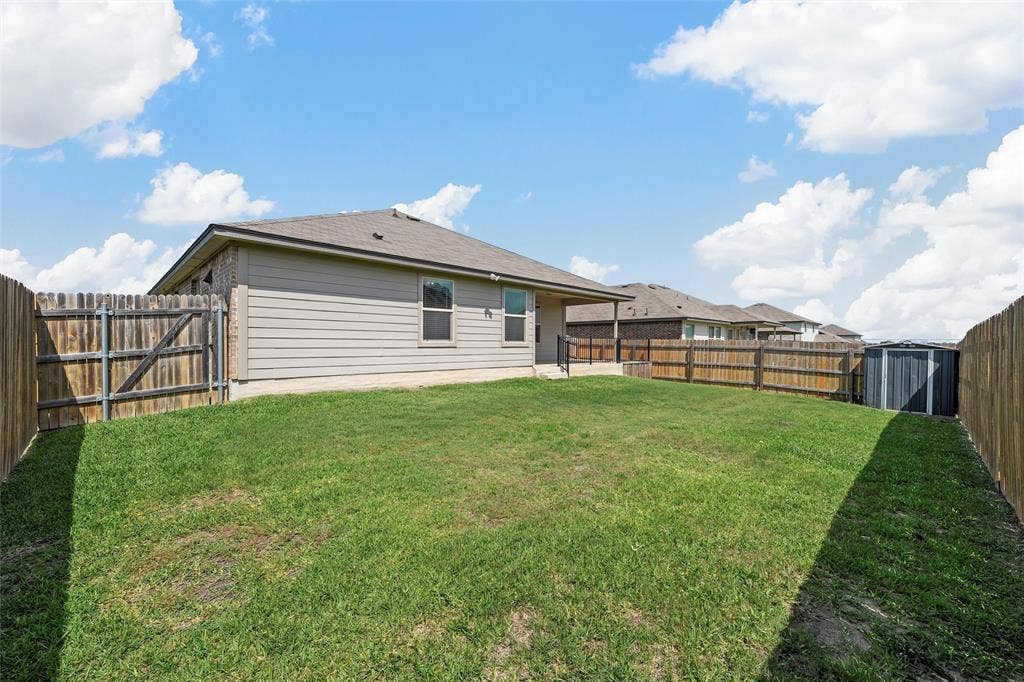 3217 Beutel Road, Lorena, TX 76655 Back of house featuring a fenced backyard, a storage unit, and a patio