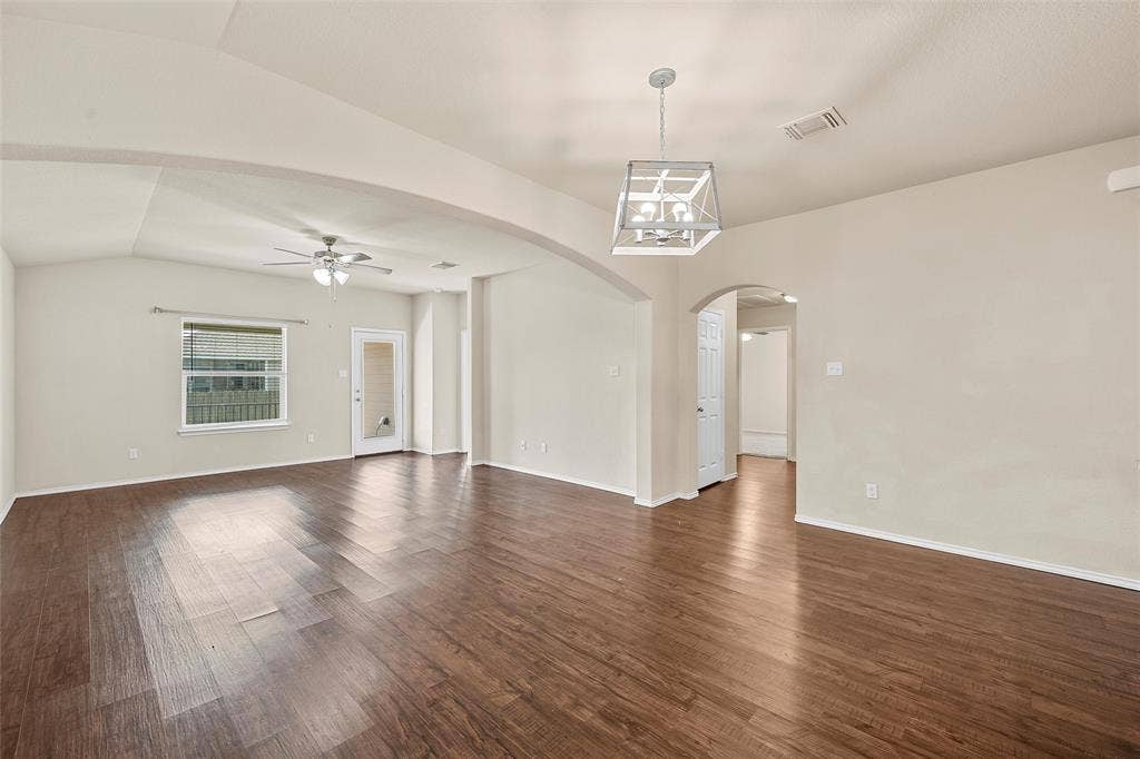 3217 Beutel Road, Lorena, TX 76655 Spare room featuring lofted ceiling, a ceiling fan, arched walkways, dark wood-style floors, and a chandelier