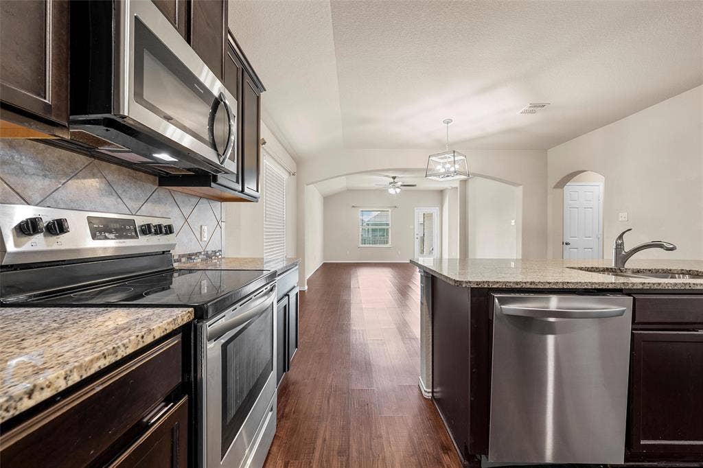 3217 Beutel Road, Lorena, TX 76655 Kitchen with stainless steel appliances, arched walkways, decorative backsplash, dark wood-type flooring, and ceiling fan