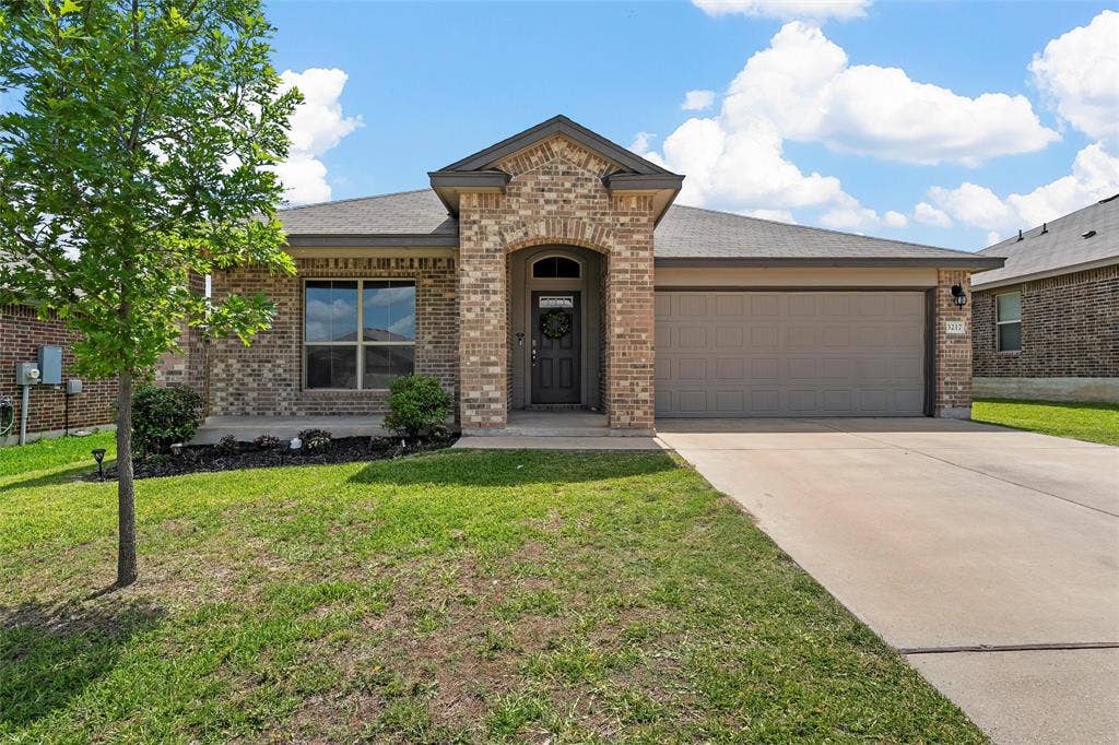 3217 Beutel Road, Lorena, TX 76655 View of front of home with a garage, brick siding, a front yard, and driveway