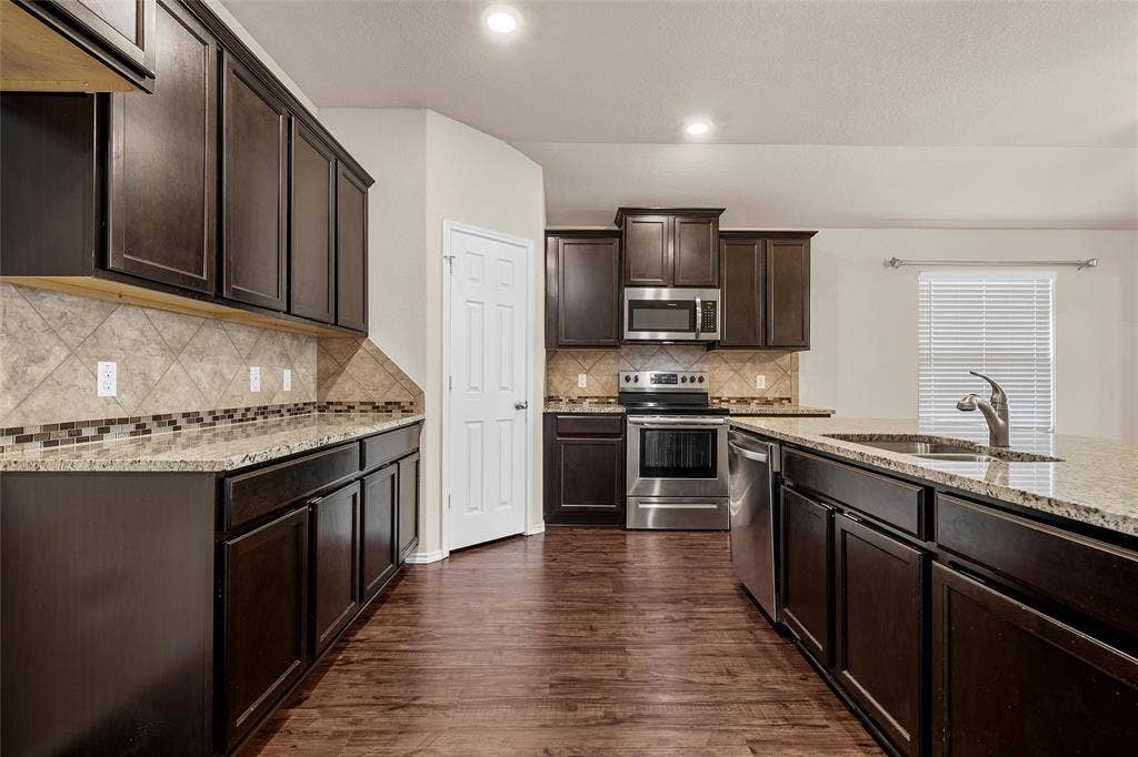 3217 Beutel Road, Lorena, TX 76655 Kitchen with stainless steel appliances, light stone countertops, dark brown cabinets, dark wood-type flooring, and recessed lighting