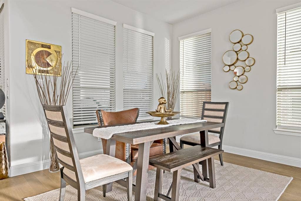Dining area featuring three windows with blinds, light wood-finish flooring, and white baseboards