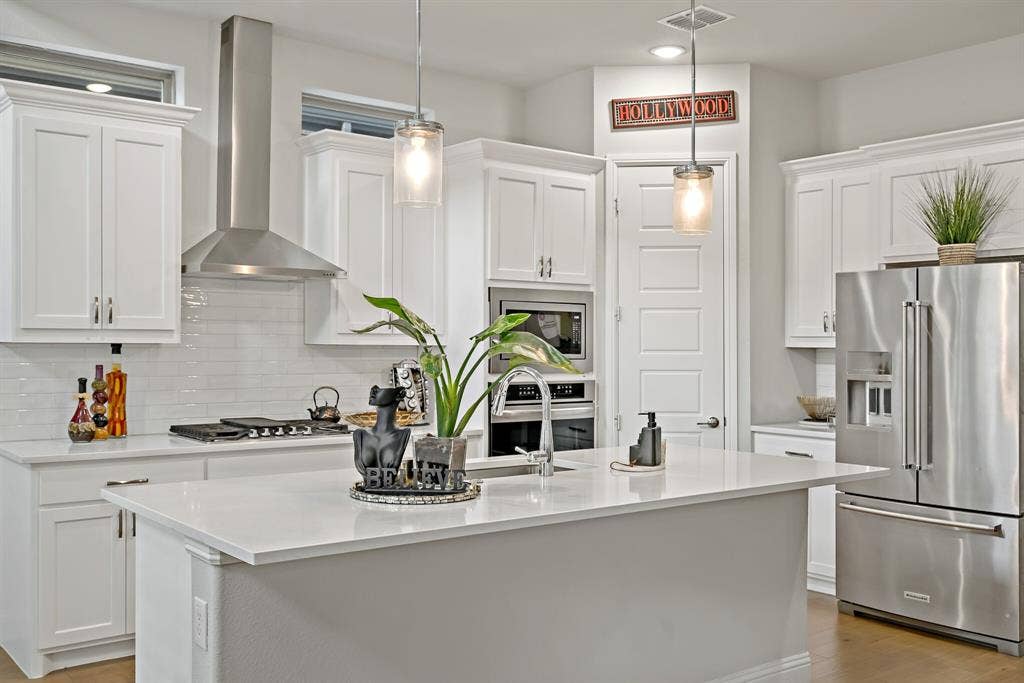 Modern kitchen featuring white cabinetry, light-toned countertops, and stainless steel appliances