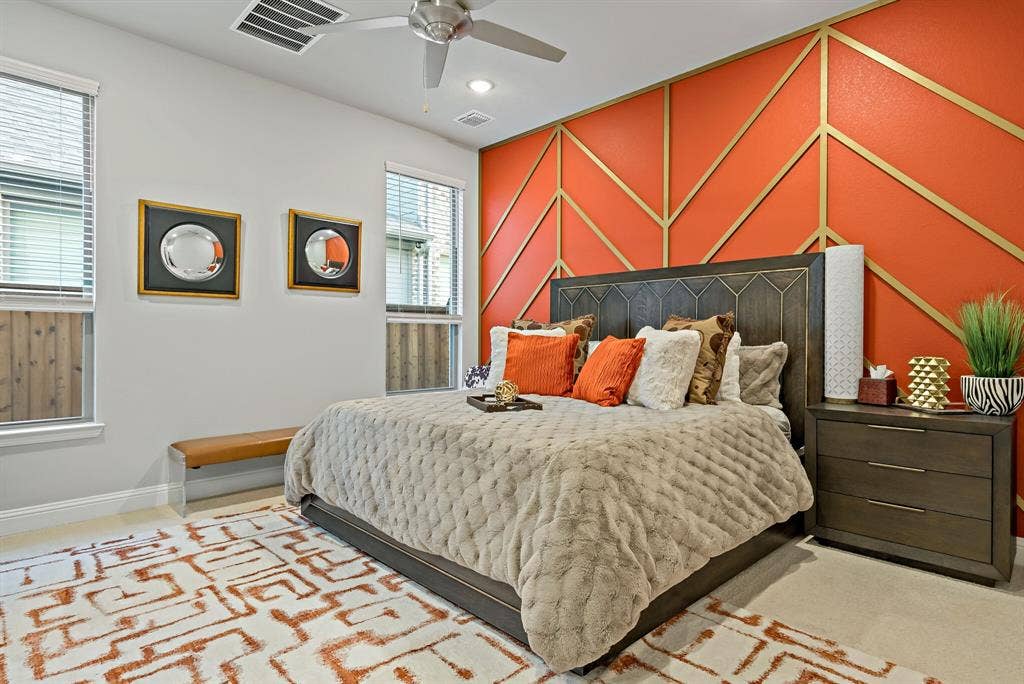 Bedroom featuring a decorative accent wall with geometric gold detailing on an orange background