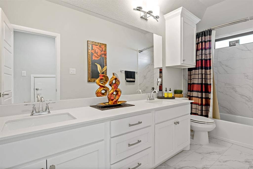 Contemporary bathroom featuring a double vanity with integrated sinks and chrome fixtures, white cabinetry, and a full-width mirror