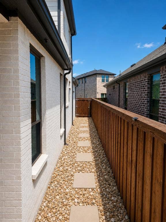 Side yard featuring a paver stone pathway set in gravel, a wood privacy fence, and a gate