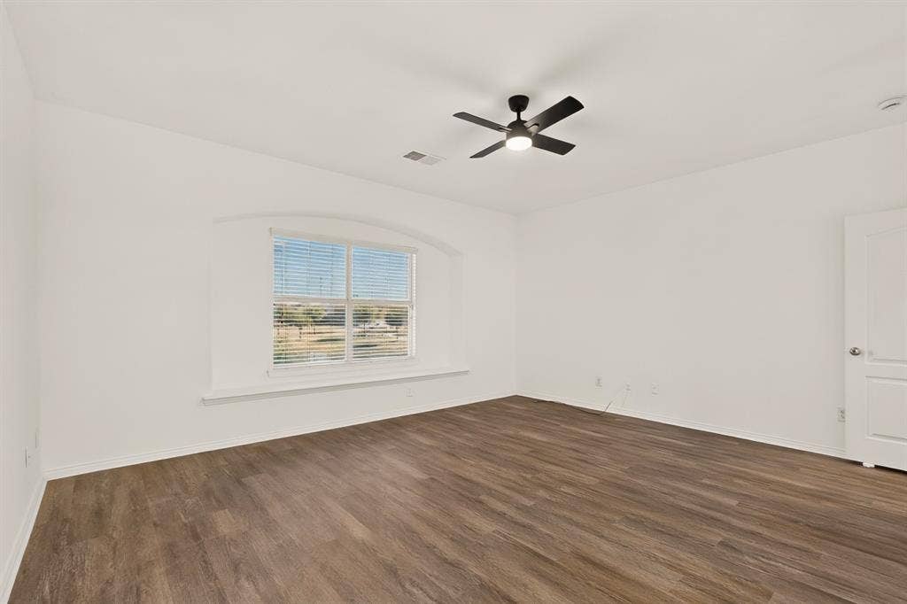 14908 Riverside Drive, Little Elm, TX 75068 Wood-finish flooring, white walls, arched window, ceiling fan with integrated lighting, and a white panel door