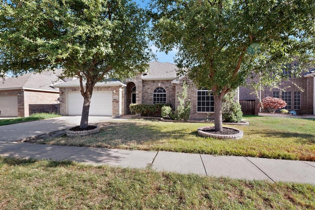 14908 Riverside Drive, Little Elm, TX 75068 Brick exterior with arched entry, dual garage doors, arched windows, and mature trees