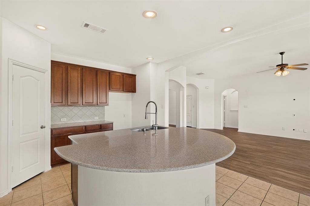 14908 Riverside Drive, Little Elm, TX 75068 Kitchen featuring a curved island with countertop, stainless steel sink, and gooseneck faucet