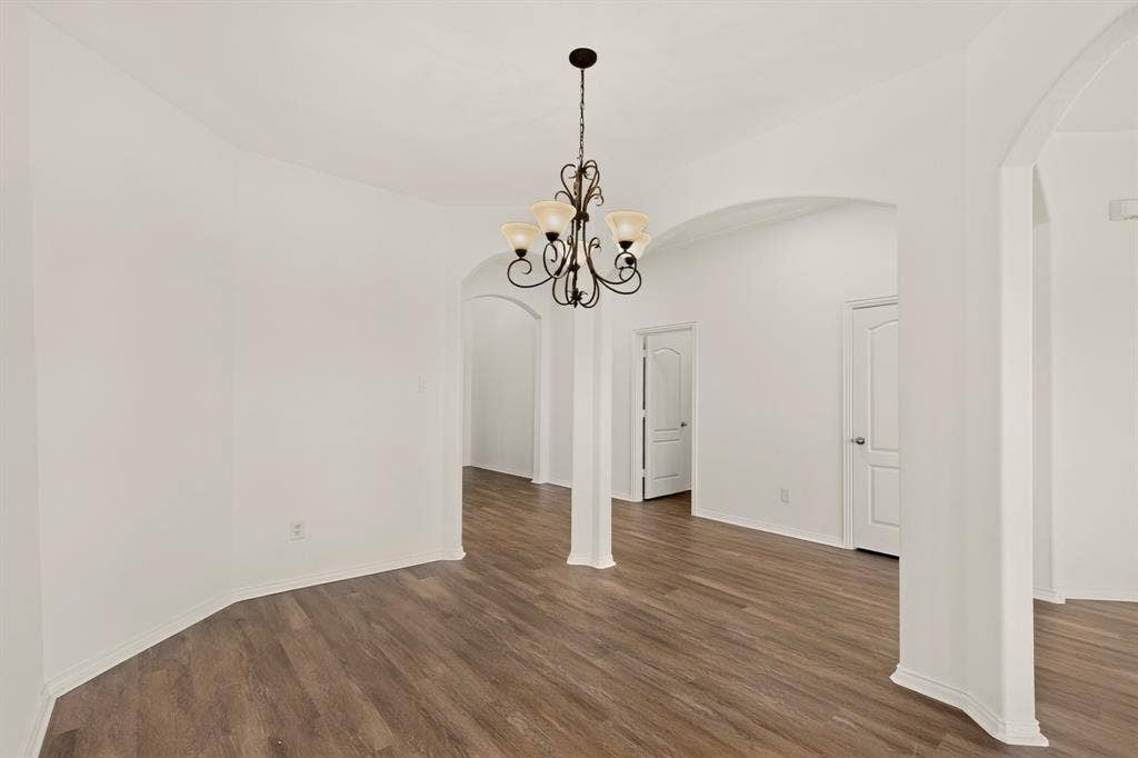 14908 Riverside Drive, Little Elm, TX 75068 Wood-finish flooring, arched doorways, interior columns, and a decorative chandelier