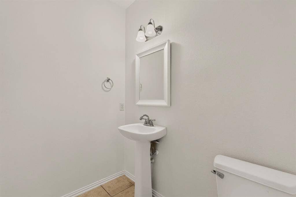 14908 Riverside Drive, Little Elm, TX 75068 Pedestal sink, wall-mounted mirror, ceramic tile flooring, and wall-mounted vanity lighting